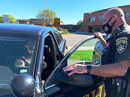 Shayla Colarusso inside Deputy Sean Lyons's patrol car, with Sean outside