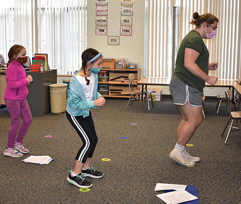 2 students and Josh Hoyt practicing dance steps in classroom