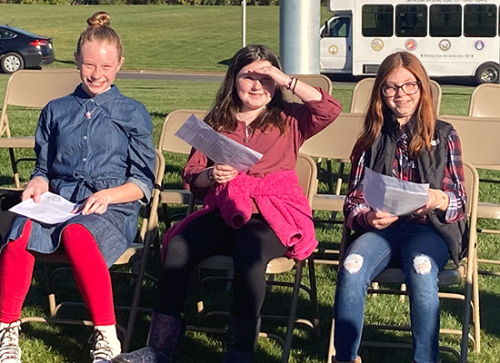 3 students seated at cemetery event