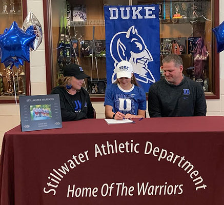 Gianna signs letter as parents look on