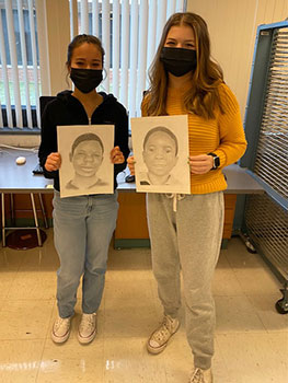 students holding portraits they created