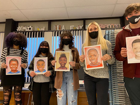 students and teacher holding portraits they created