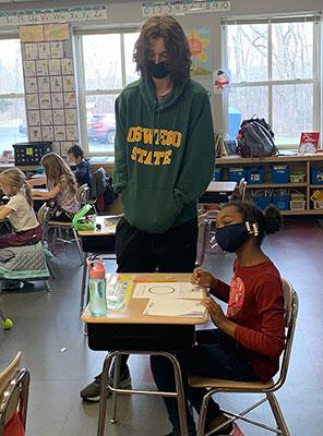 HS student working with 2nd grade student at her desk