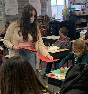 HS student working with 2nd grade student at her desk