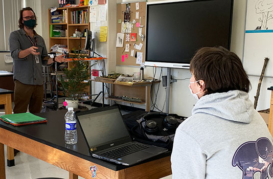 HS teacher talking to student in classroom