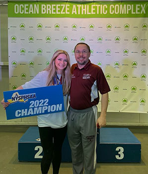 Gianna holding sign, standing with her coach