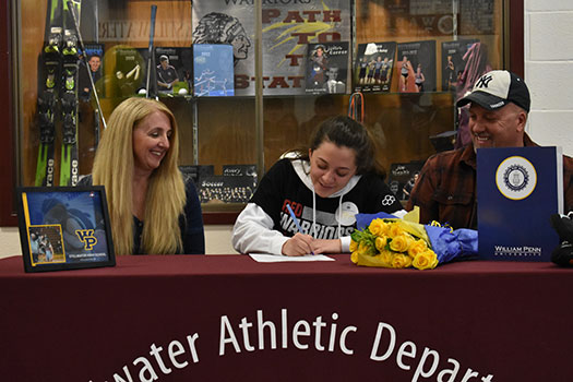 Lexi signing letter as parents Laura and Steve look on