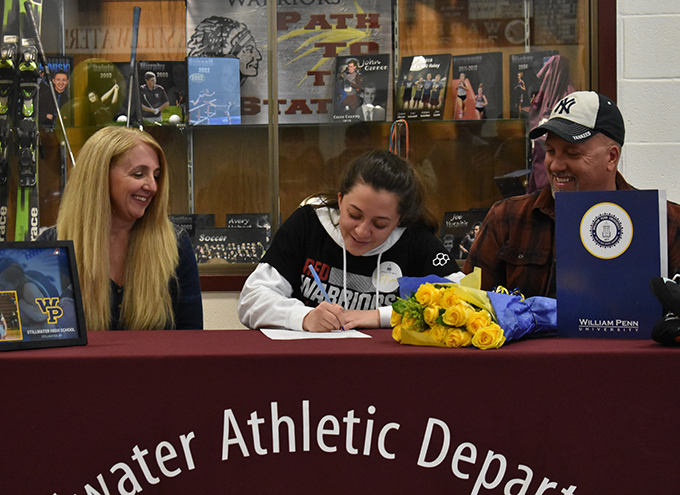Lexi LaFountain signs letter as parents look onof intent