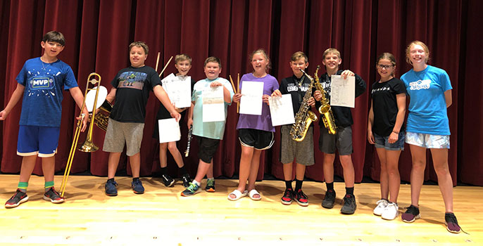 group of students standing on stage holding instruments