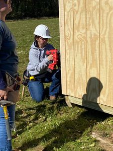 Maddy with a power tool working on shed