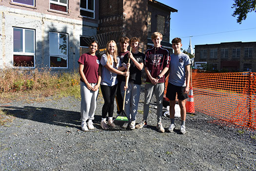 group of students holding rakes