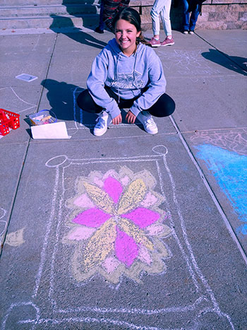 student sitting by their rangoli