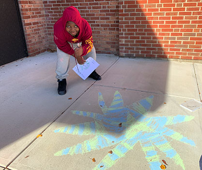 student standing by their rangoli