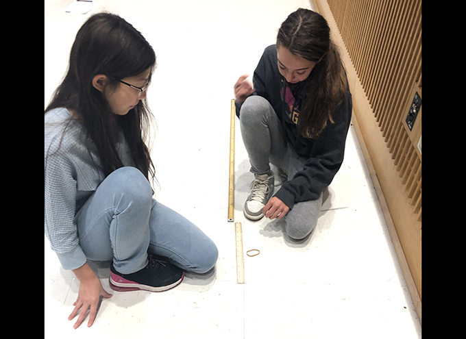 2 students with ruler on floor