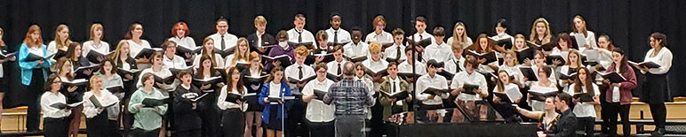 group of students standing and singing in an auditorium