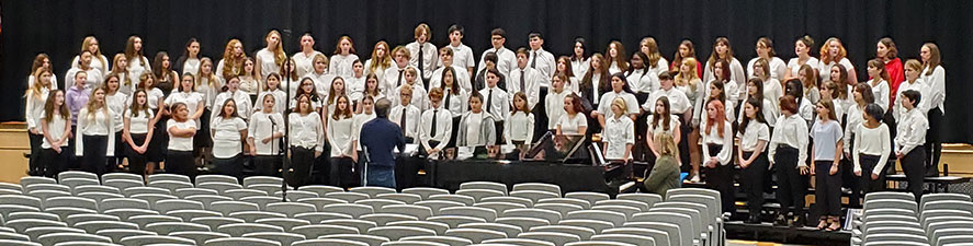group of students standing and singing in an auditorium