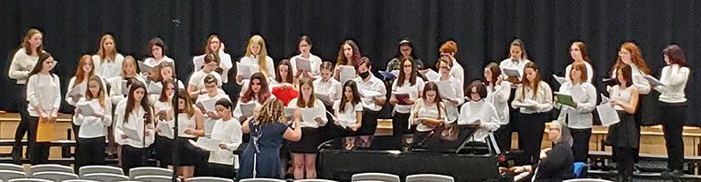 group of students standing and singing in an auditorium