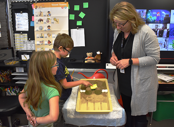 2 students and teacher conducting sand erosion experiment