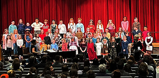 students singing in a group on stage