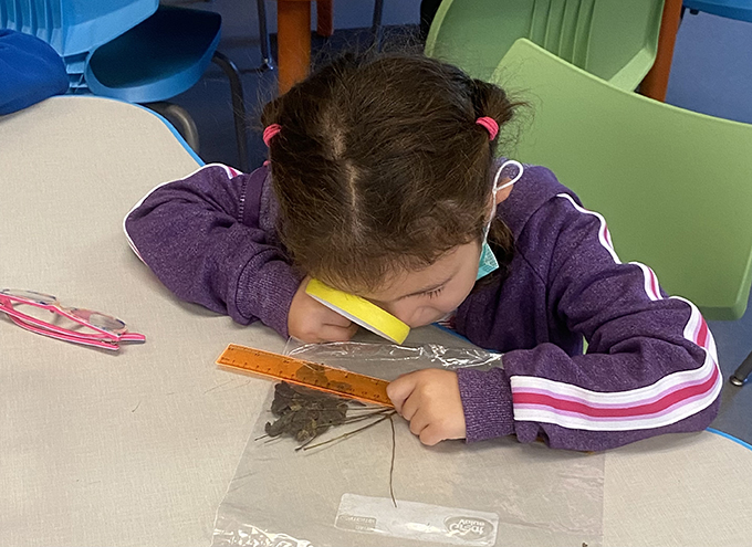 student looks through a magnifying glass