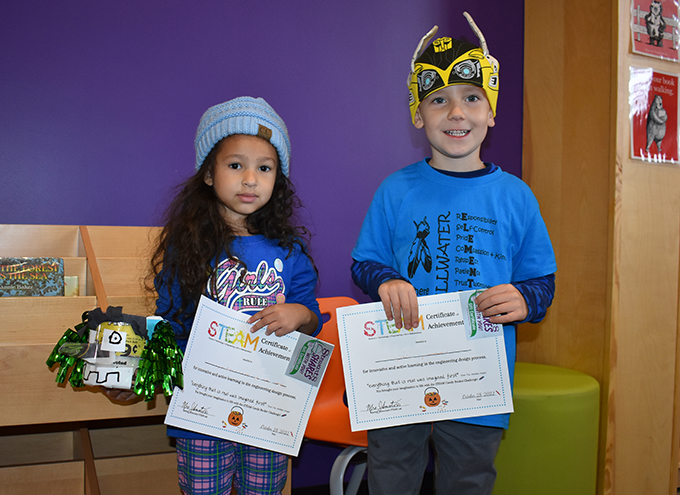 2 students holding certificates and their handmade buckets