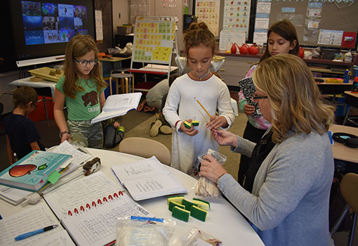 teacher with students at a table with science kit supplies