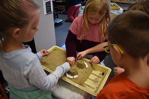 3 students working with sand tower science kit