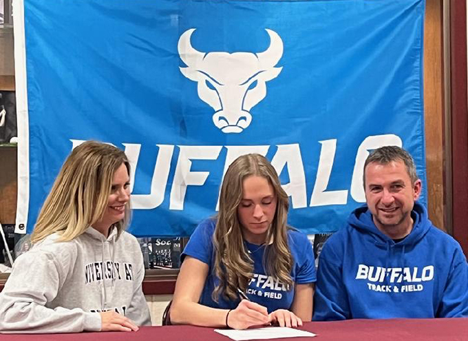 student signing letter as parents look on