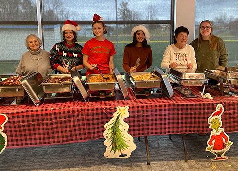 students and adults standing behind food serving table