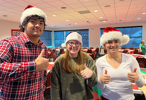 3 students in Santa hats giving thumbs up 