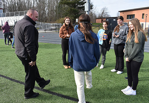 Officer Lyons and student raise their feet while other students look on