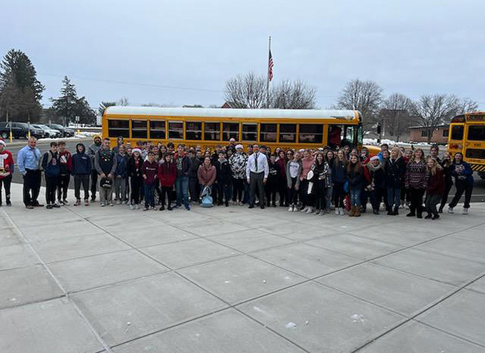 7th grade standing in a group by bus before museum field trip