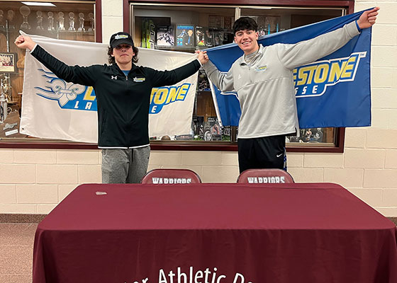 2 students holding Limestone University banners above their shoulders