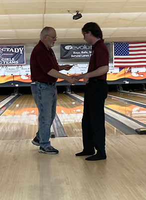 Bowler receiving award from adult