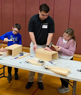 adult teaches 2 students how to build a toolbox