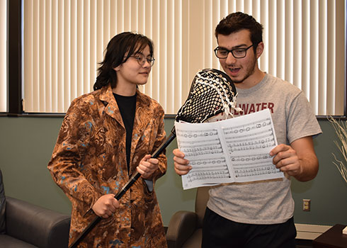 Nurshinta holding lacrosse stick while Amoun holds music and pretends to sing into it