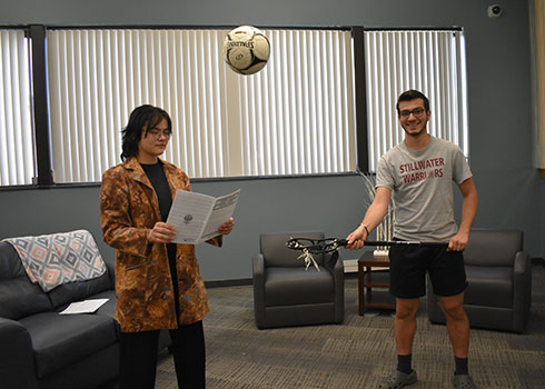 Nurshinta reading music while soccer ball is airborne between her and Amoun, who's holding a lacrosse stick