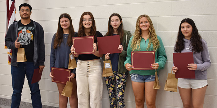 6 students standing in a group holding certificates