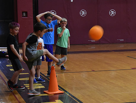 student kicking ball in the gym