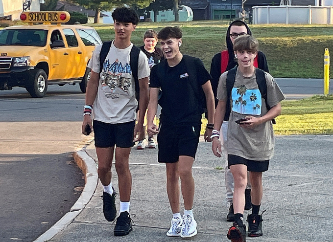 Three students smiling as they walk on the sidewalk.