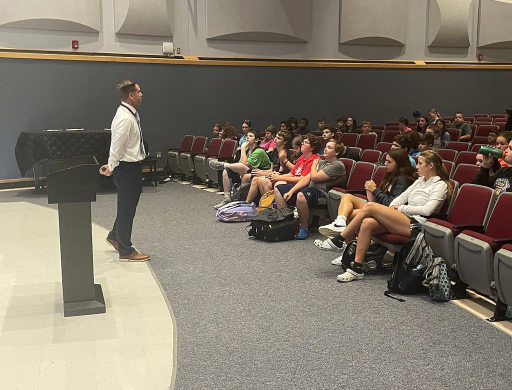 Principal Hulihan speaking to students in the auditorium.