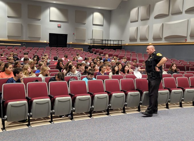 SRO speaking to a group of students in the auditorium.