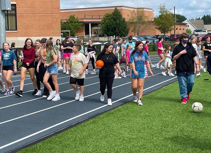 Group of students walking onto the turf field.