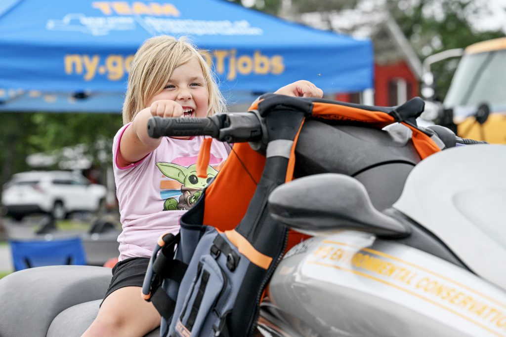 Little girl pretending to ride a snowmobile.