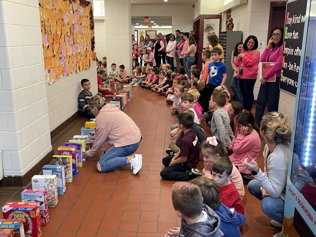 Students and staff lining the hallways with cereal boxes lined up in front of them.