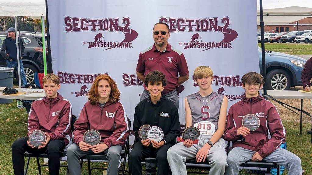 Coach and runners with awards smiling for a group photo.