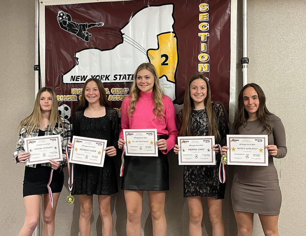 Five girls varsity soccer players holding certificates and smiling for a photo.