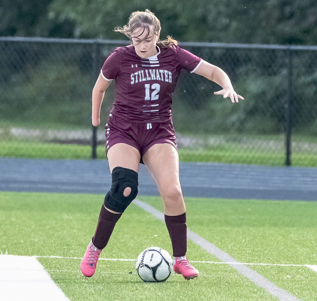 Girl soccer player on field with soccer ball at her feet.