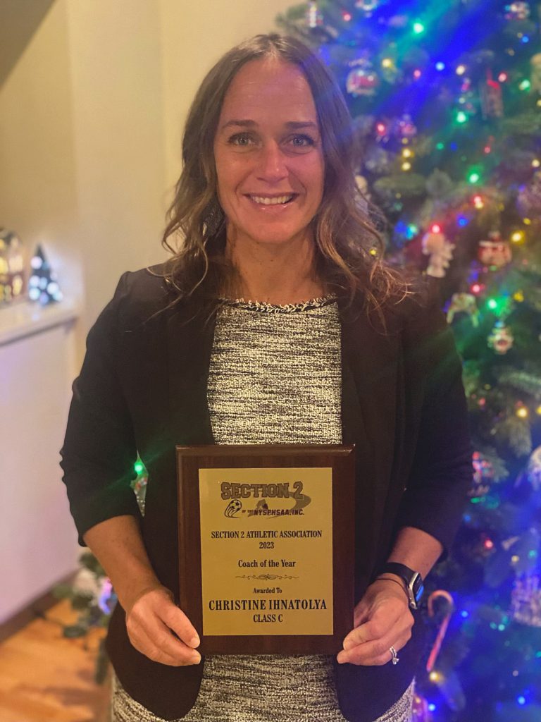 Woman holding award plaque and smiling.