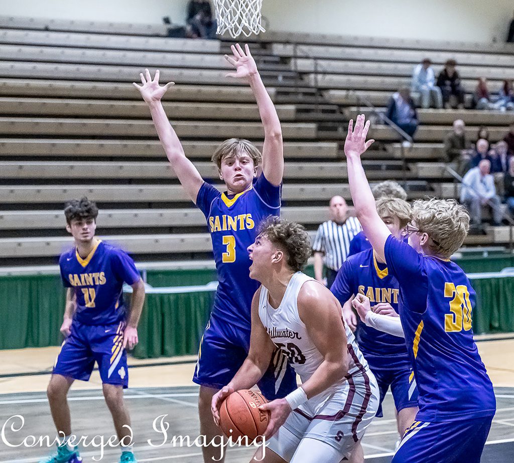 Player holding basketball attempting to take a shot while another player blocks him.